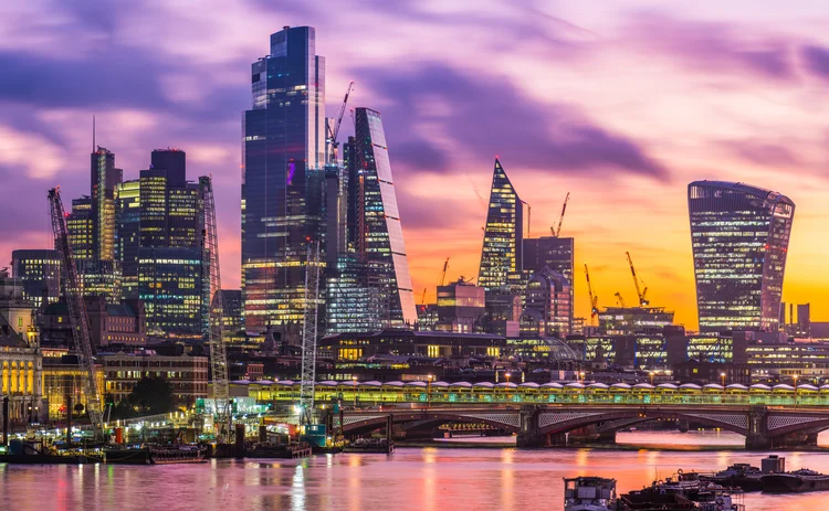 Golden light of sunrise illuminated the historic dome of St. Paul’s Cathedral and the futuristic spires of City skyscrapers overlooking the River Thames in the heart of London, UK.