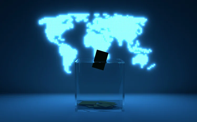 A transparent ballot box in front of a illuminated map of the world and a vote cast in it. 2024 is a year in which elections almost all over the world coincide with the same year. This year, billions of people will go to the polls and vote for democracy.