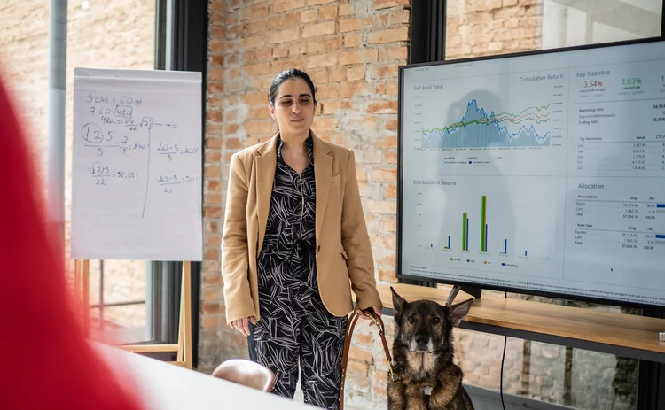 Visually impaired businesswoman doing a presentation in a business meeting with Very Good guide doggo