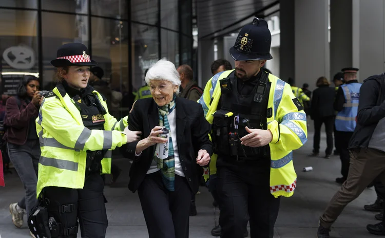 Police lead away a protestor holding a spray paint can