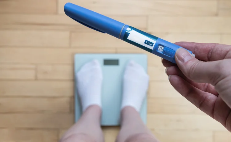 Ozempic Insulin injection pen for diabetics and weight loss. Woman weighs herself and holds Ozempic in her hand. Weight loss concept.