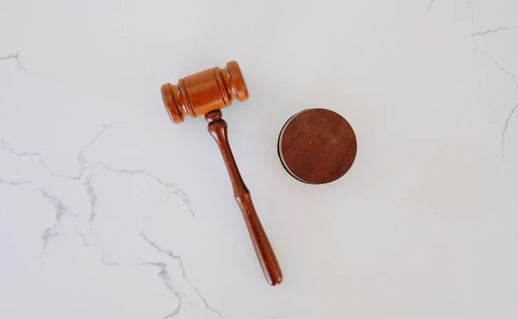 A wooden gavel on a white marble backdrop