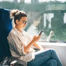 Young woman traveling by train and using phone.