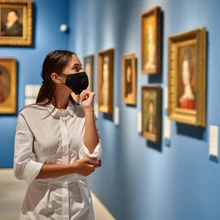 woman visitor wearing an antivirus mask in the historical museum looking at pictures