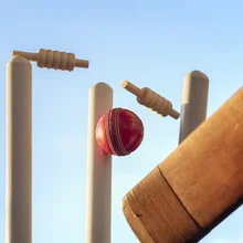 Cricket bat and cricket ball hitting wicket stumps knocking bails out